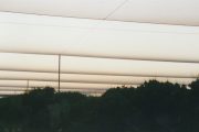 Parallel horizontal beams against a dusky sky with silhouetted trees below
