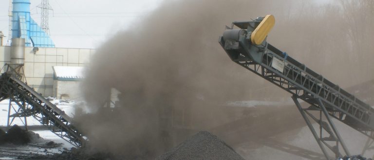 Dust cloud from conveyor belt at industrial site with snow on ground