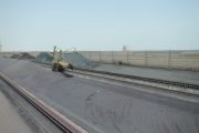 Aerial view of coal piles and machinery at an industrial site with wind fences