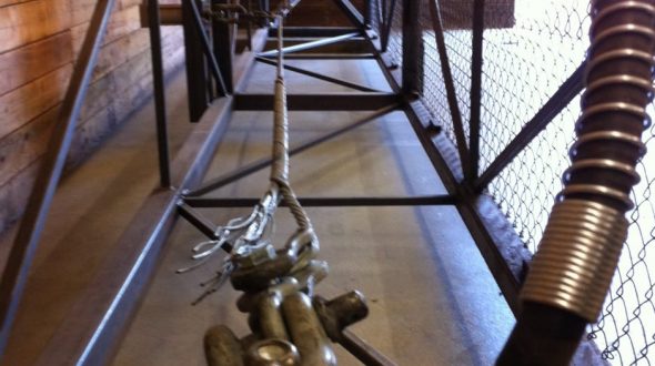 A metal cage-like structure with a chain and mechanical components inside