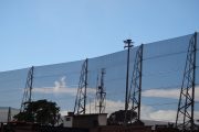 A large industrial wind fence stretches across the image against a clear blue sky
