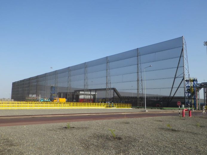 A large industrial wind fence with a clear blue sky in the background