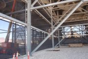 Metal framework and netting structure with construction equipment and safety cones visible