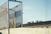 A tall, metal-framed wind fence with fabric panels stands against a clear sky
