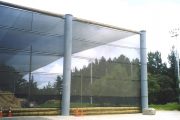 A large, translucent wind fence supported by cylindrical pillars stands outdoors
