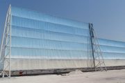 A large blue and white wind fence structure stands against a clear sky