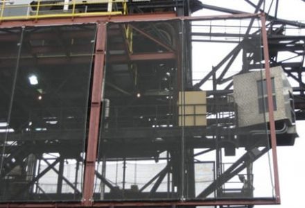 A large industrial structure with metal framing and mesh panels, possibly a wind fence or dust control system