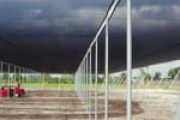 A large open-sided structure with a dark overhead canopy supported by metal poles