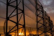 A large industrial fence structure with translucent panels against a sunset sky