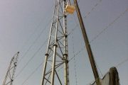 A tall metal tower with a crane lifting equipment against a clear sky