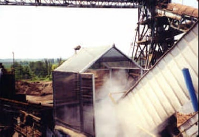 An industrial site with a metal structure releasing steam or dust into the air