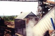 An industrial site with a metal structure releasing steam or dust into the air