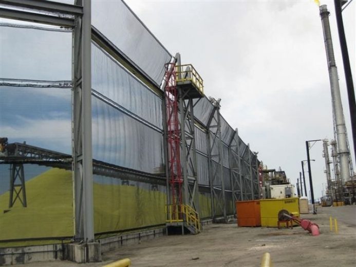 A large industrial wind fence with a red staircase and yellow platform